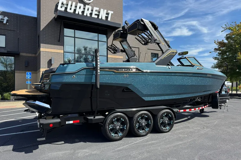 Slide: The Image of 2025 MasterCraft XStar 25 boat on trailer, parked outside a building. - 3