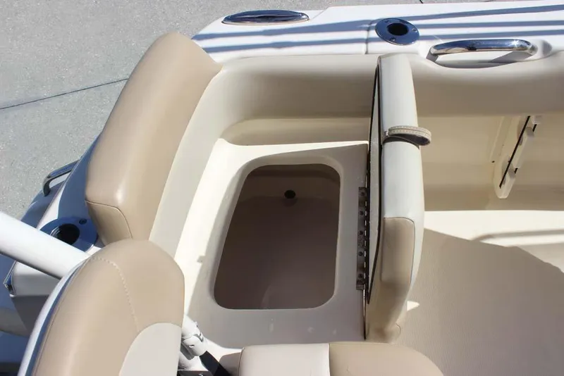 Slide: The Image of 2021 Scout 195 Sport Dorado boat interior with beige seating and motor, parked near vehicles. - 24