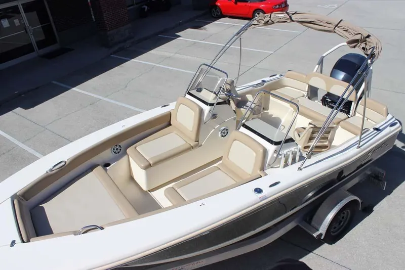 Slide: The Image of 2021 Scout 195 Sport Dorado boat with beige seating and bimini top in a parking lot. - 3