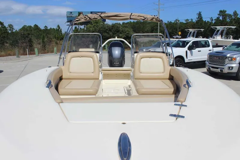 Slide: The Image of 2021 Scout 195 Sport Dorado boat with seating and outboard motor in a parking area. - 5