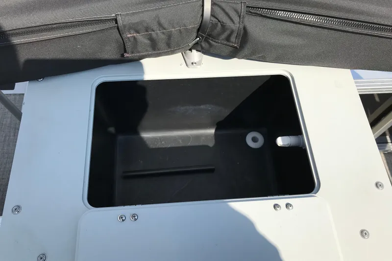 Slide: The Image of 2024 Avalon VENTURE FISH-N-CRUISE storage compartment with black cover and secure fastenings. - 24