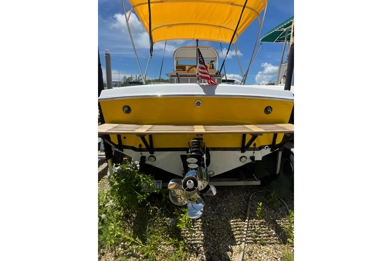 Slide: The Image of 1978 Formula boat with yellow hull, American flag, and canopy, parked on gravel. - 4