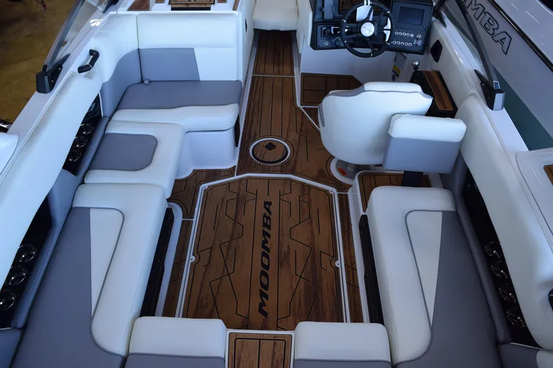 Slide: The Image of 2025 Moomba Craz boat interior with white and gray seating, wood flooring, and modern dashboard. - 14