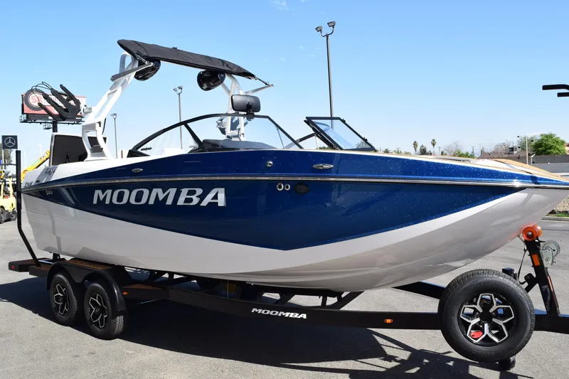 Slide: The Image of 2025 Moomba Craz boat on trailer, blue and white design, parked outdoors. - 4