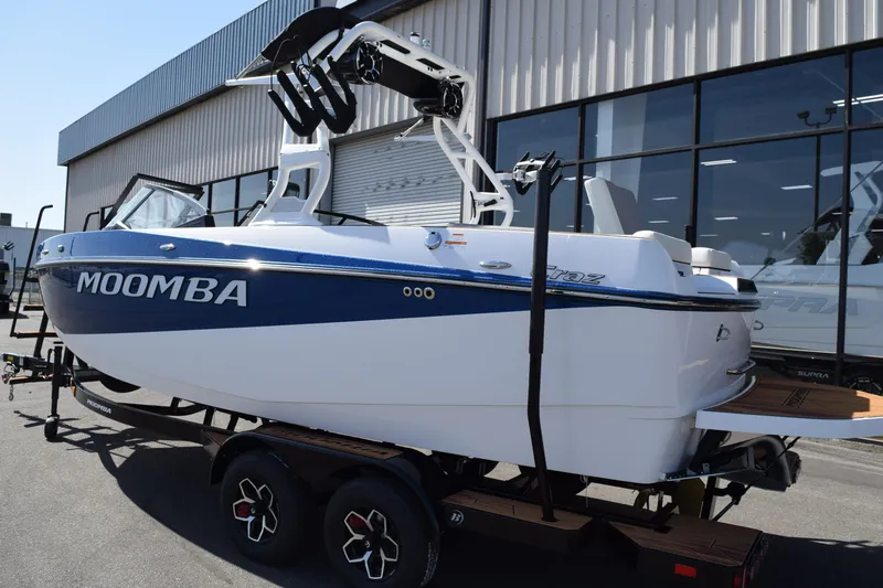 Slide: The Image of 2025 Moomba Craz boat on trailer, blue and white, parked outside a building. - 5