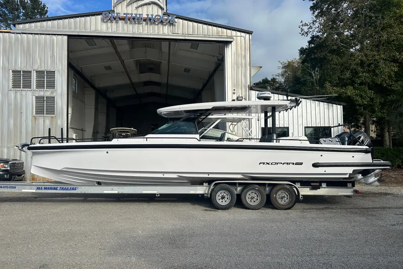 Slide: The Image of 2022 Axopar 37 Sun Top boat cruising on a calm river with a scenic background. - 2