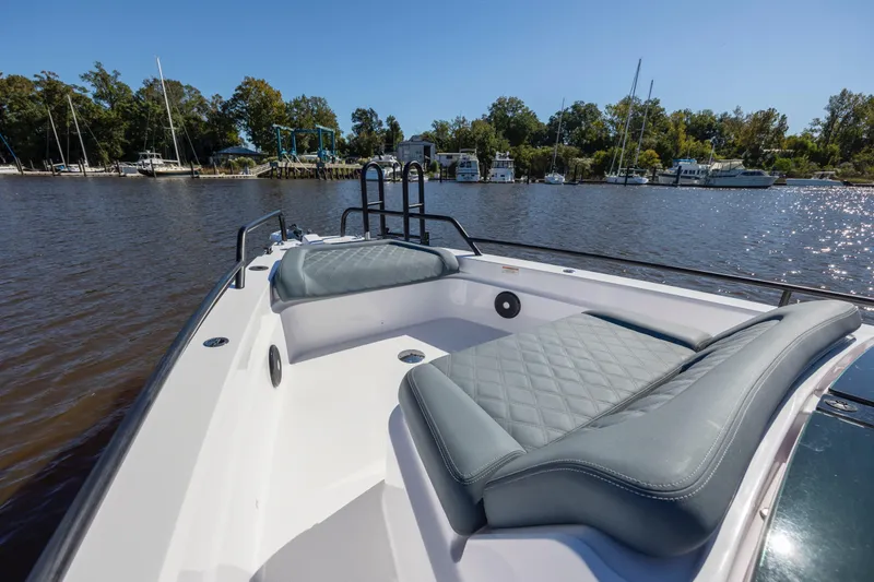 Slide: The Image of 2022 Axopar 37 Sun Top boat with cushioned seating, docked near a marina. - 23