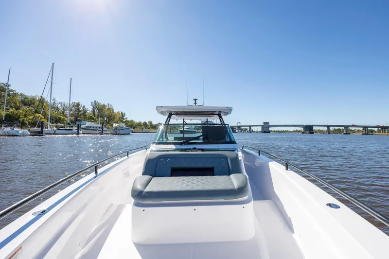 Slide: The Image of 2022 Axopar 37 Sun Top boat on a sunny day, docked near a marina. - 25
