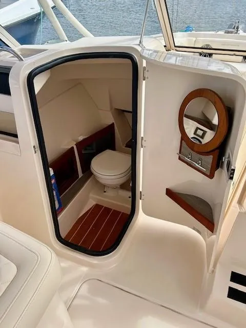 Slide: The Image of 2021 Grady-White Freedom 235 boat interior with compact bathroom and wooden accents. - 10