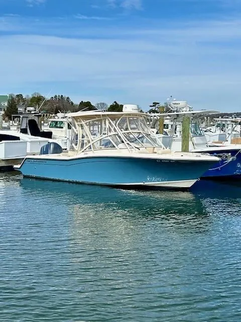 Slide: The Image of 2021 Grady-White Freedom 235 boat docked in a marina under a clear blue sky. - 2