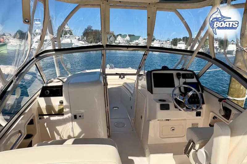 Slide: The Image of 2021 Grady-White Freedom 235 boat interior with helm, steering wheel, and marina view. - 5