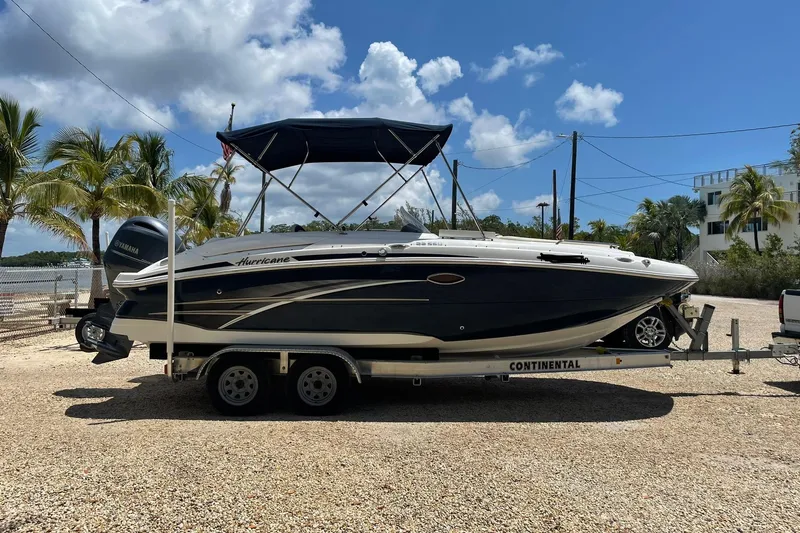 Slide: The Image of 2017 Hurricane SunDeck 2200 OB boat on trailer, parked near palm trees under blue sky. - 2