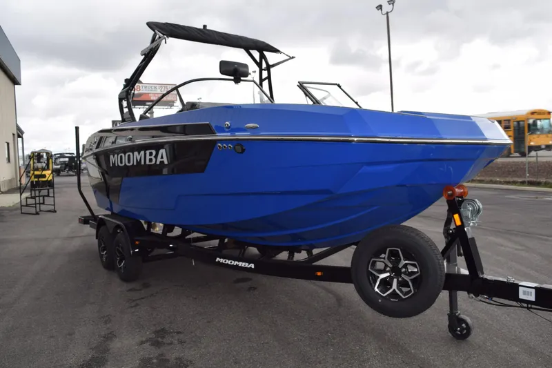 Slide: The Image of 2025 Moomba Max boat in vibrant blue on a trailer, parked outdoors. - 2