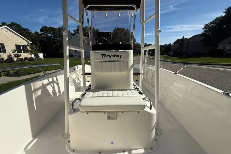 Slide: The Image of 2022 Bayliner Trophy T18Bay boat interior with seating and console, parked in a residential area. - 13