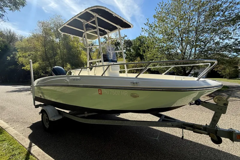 Slide: The Image of 2022 Bayliner Trophy T18Bay boat on trailer, parked on a sunny street. - 2