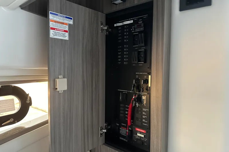 Slide: The Image of Electrical panel inside 2026 Sea Ray Sundancer 320 yacht, featuring control switches and safety notices. - 25