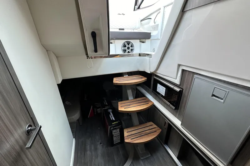 Slide: The Image of Interior of 2026 Sea Ray Sundancer 320, featuring wooden steps and modern cabinetry. - 26