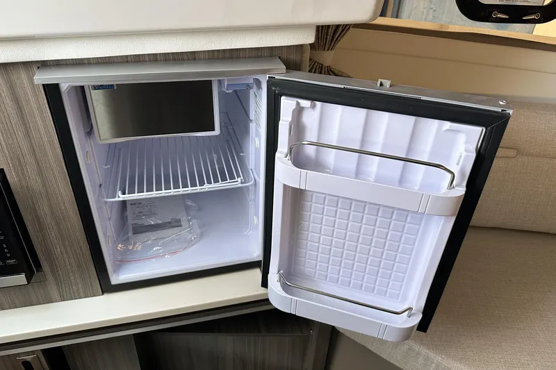 Slide: The Image of Open mini fridge inside 2026 Sea Ray Sundancer 320 yacht, showcasing interior storage space. - 28
