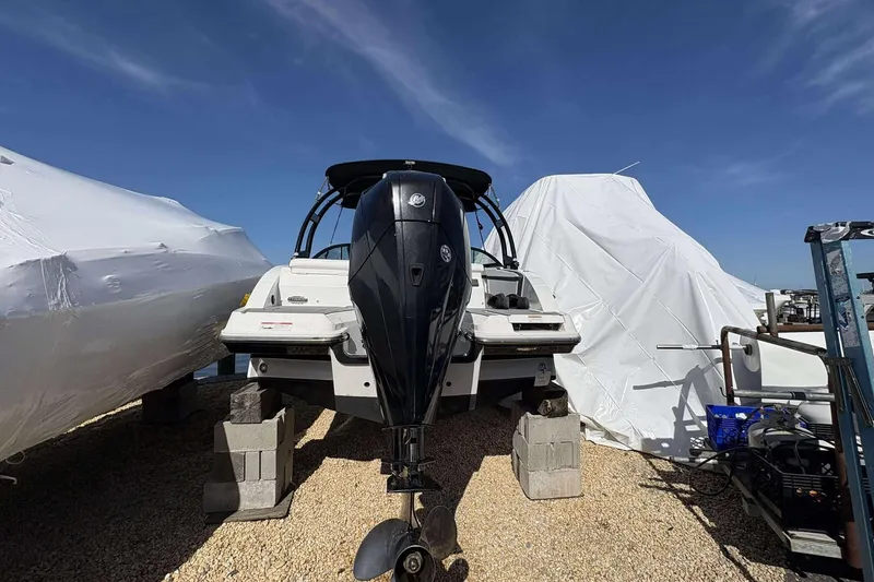 Slide: The Image of 2020 Monterey M-225 boat on blocks, covered, with outboard motor, under clear blue sky. - 15