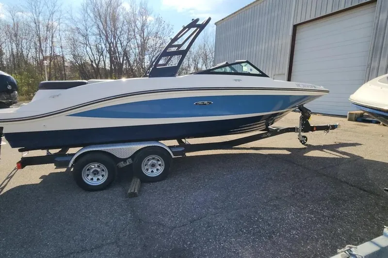 Slide: The Image of 2021 Sea Ray SPX 210 Outboard boat on trailer, parked outdoors near a warehouse. - 4