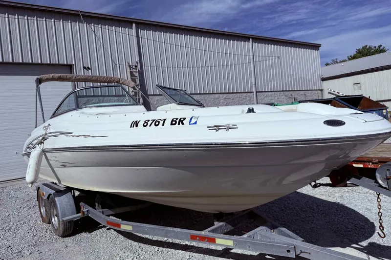 Slide: The Image of 2000 Sea Ray 210 Sundeck boat on trailer, parked outside a metal building. - 5