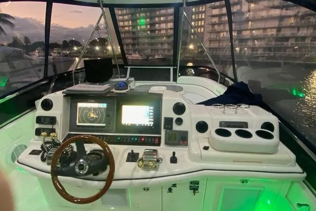 Slide: The Image of 2007 Sea Ray 52 Sedan Bridge helm with illuminated controls and navigation screens at dusk. - 17