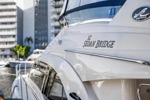 Slide: The Image of 2007 Sea Ray 52 Sedan Bridge yacht docked in marina, cityscape background. - 19