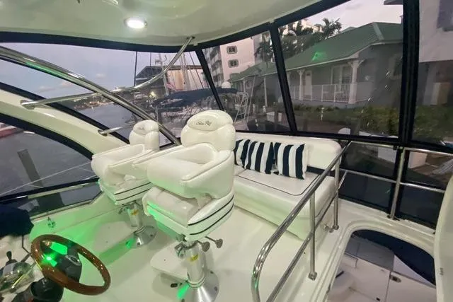 Slide: The Image of 2007 Sea Ray 52 Sedan Bridge interior with white seating and striped cushions, dockside view. - 42