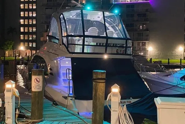 Slide: The Image of 2007 Sea Ray 52 Sedan Bridge yacht docked at night, illuminated with blue lights. - 53