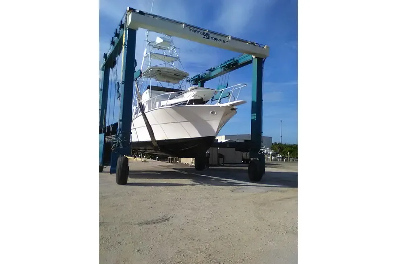 Slide: The Image of 1976 Viking 40 Convertible yacht with tower on a travel lift under clear blue sky. - 2