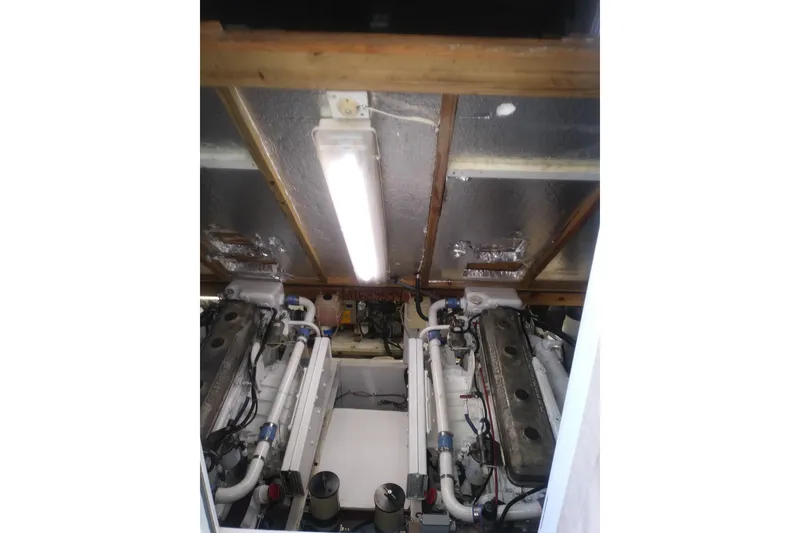 Slide: The Image of Engine room of a 1976 Viking 40 Convertible boat, featuring dual engines and overhead lighting. - 3