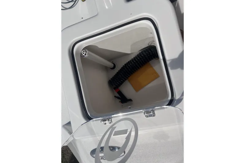 Slide: The Image of Open storage compartment on 2026 Defiance Catalina 210 boat, showing coiled hose and envelope. - 14