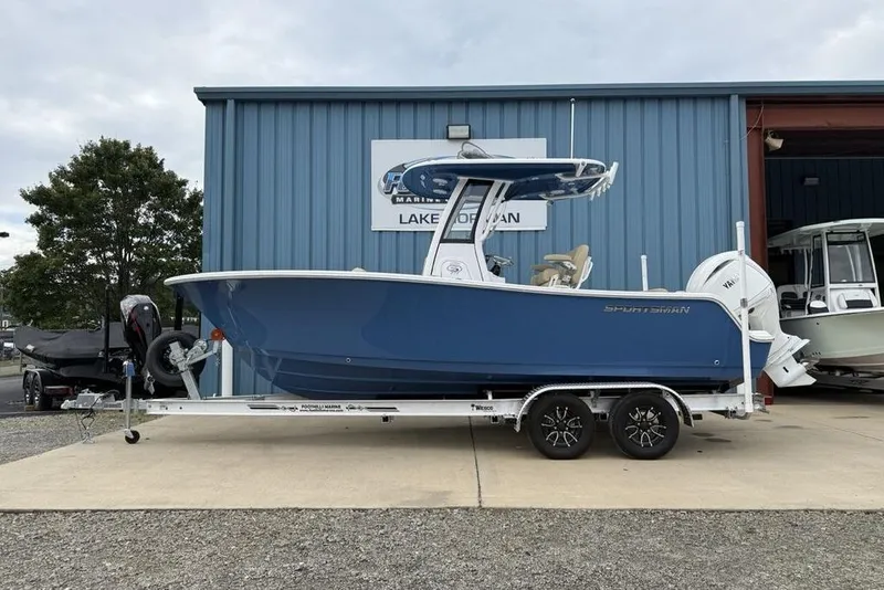 The Image of 2026 Sportsman Open 212 Center Console boat on trailer outside marine shop. - 1