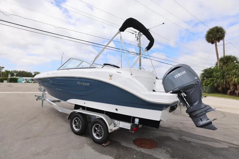 Slide: The Image of 2026 Hurricane SunDeck 235 OB boat with Yamaha 200 engine, parked outdoors. - 23