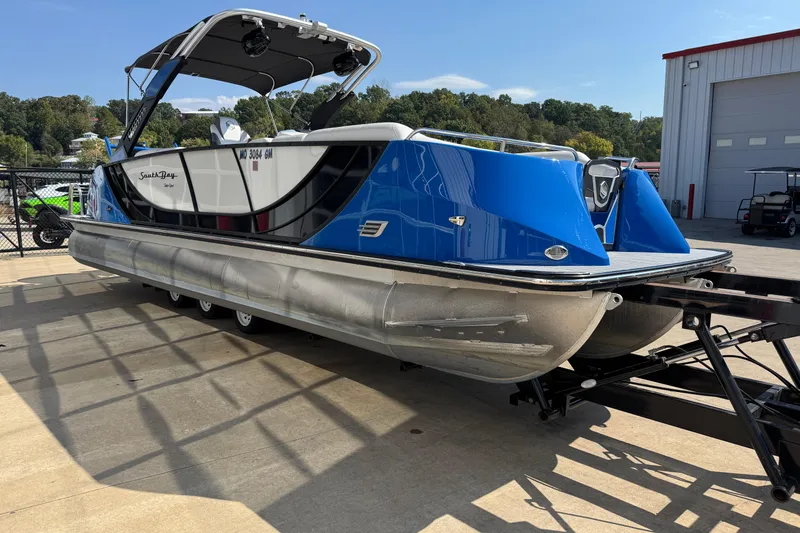Slide: The Image of 2022 South Bay 25 Sport CR9-DC pontoon boat on trailer, blue and white design. - 4
