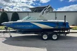 Slide: The Image of 2012 MasterCraft X25 boat on trailer, blue and white design, parked outdoors. - 10