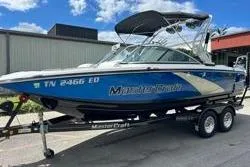 Slide: The Image of 2012 MasterCraft X25 boat on trailer, blue and white, parked outdoors. - 14