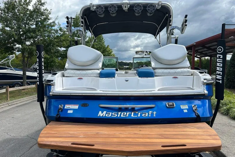 Slide: The Image of 2012 MasterCraft X25 boat with blue and white design, parked outdoors. - 3