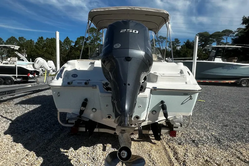 Slide: The Image of 2023 Key West 239 DFS boat with powerful outboard motor, parked on gravel lot. - 3