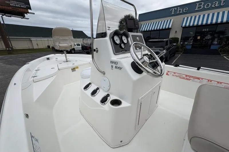 Slide: The Image of 2015 NauticStar 1910 NauticBay boat with center console and steering wheel, parked outdoors. - 14