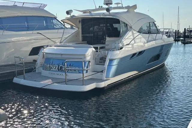 The Image of 2020 Riviera 4800 Sport Yacht docked in marina, rear view. - 0