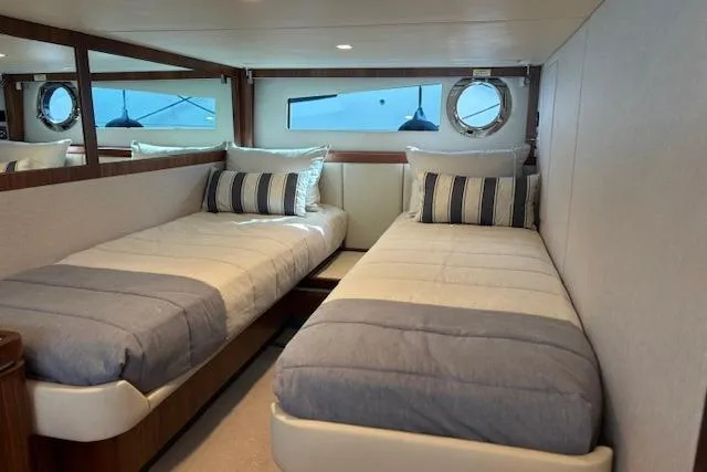 Slide: The Image of 2020 Riviera 4800 Sport Yacht cabin with twin beds and nautical decor. - 17