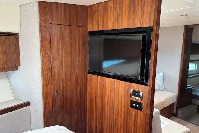 Slide: The Image of Interior of 2020 Riviera 4800 Sport Yacht with wood paneling and mounted TV. - 18