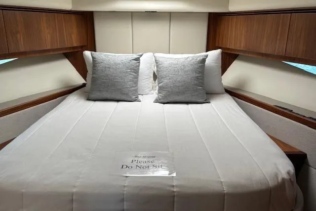 Slide: The Image of Luxurious 2020 Riviera 4800 Sport Yacht bedroom with elegant bedding and wooden accents. - 20