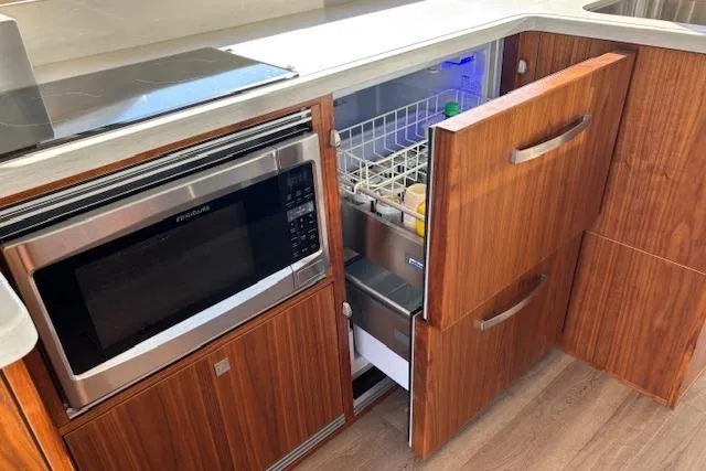 Slide: The Image of 2020 Riviera 4800 Sport Yacht kitchen with microwave and open drawer refrigerator. - 24