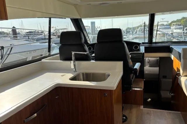 Slide: The Image of Interior of 2020 Riviera 4800 Sport Yacht with modern kitchen and helm station. - 26