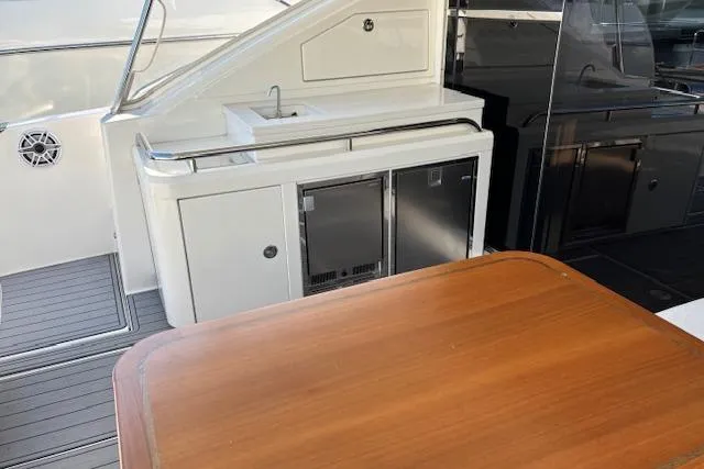Slide: The Image of 2020 Riviera 4800 Sport Yacht outdoor kitchenette with sink and wooden table. - 29