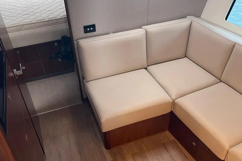 Slide: The Image of 2020 Riviera 4800 Sport Yacht interior with beige leather seating and wooden flooring. - 6