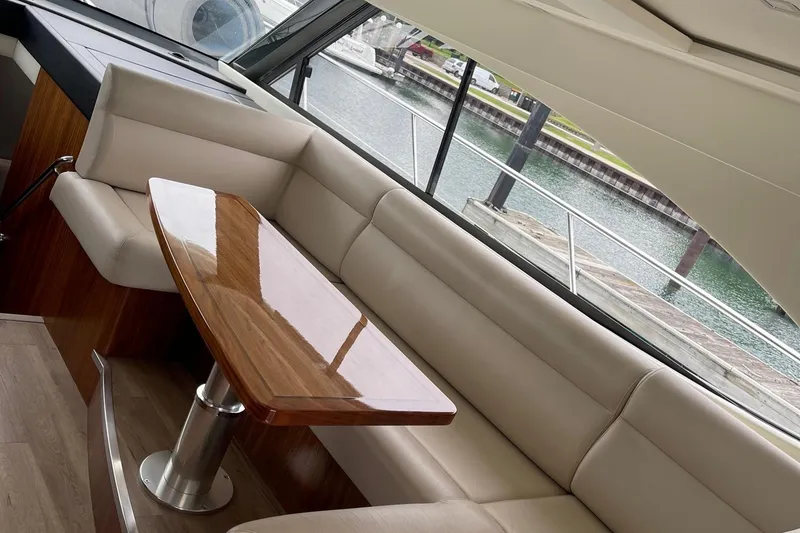Slide: The Image of Interior of 2020 Riviera 4800 Sport Yacht with elegant seating and wooden table. - 8