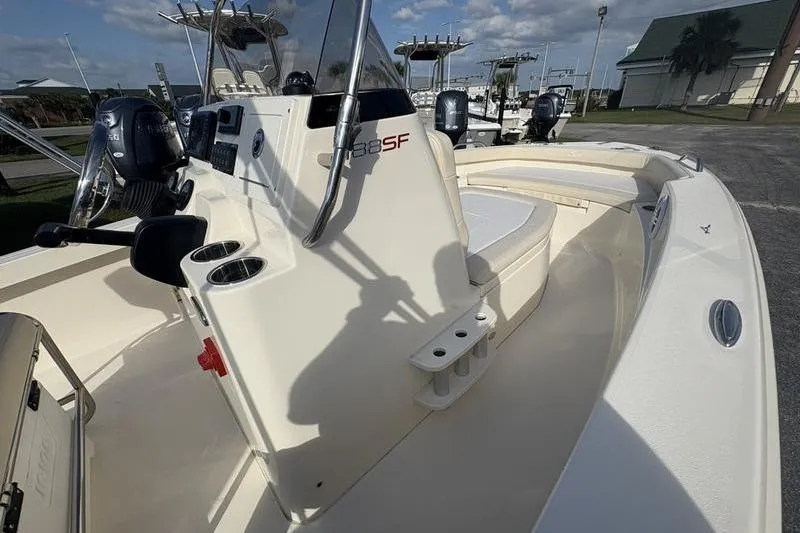 Slide: The Image of 2026 Scout 188 Sportfish boat interior with console and seating, docked under a clear sky. - 16